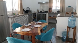 Une cuisine de taille réduite équipée d’un réfrigérateur, d’une cuisinière, d’un évier et d’une table à manger avec des chaises.