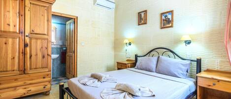 A bedroom with a bed, wooden wardrobe, and two wall-mounted lamps.