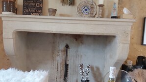A rustic interior with a fireplace, a sign above it, and a table with bread, vegetables, and a bottle of wine. - "Nouveau, a true haven of peace, close to Saint-Emilion, Bordeaux. (Saint-Vincent-de-Pertignas)