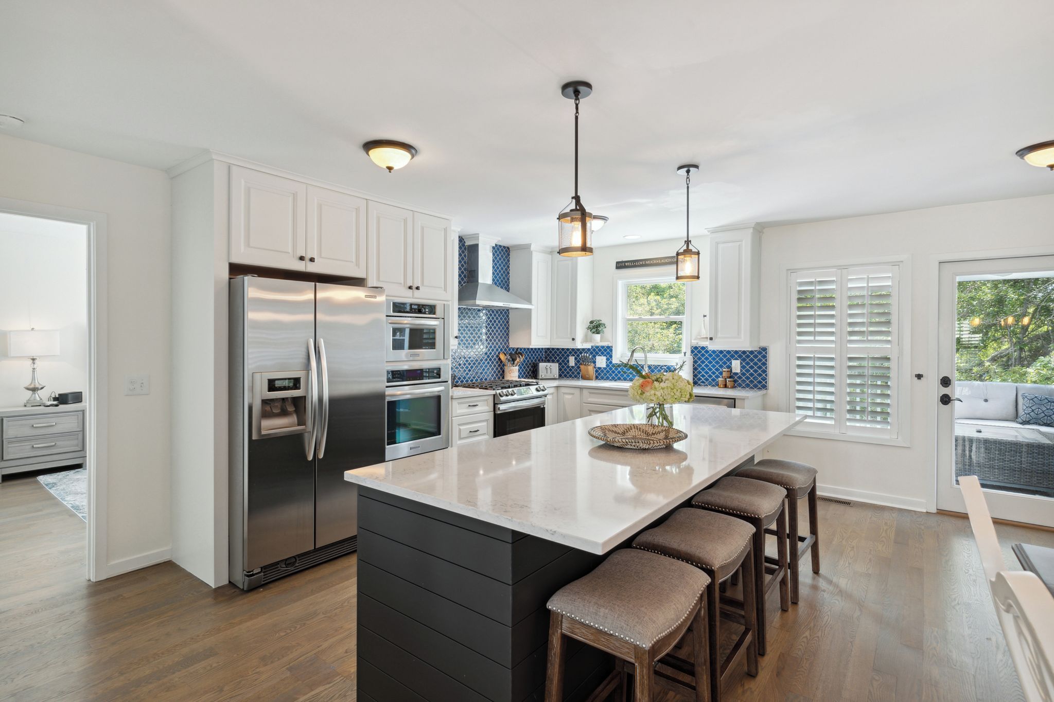 A modern kitchen with a central island, stainless steel appliances, and a view to the outdoors.