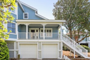 Ein zweistöckiges Haus mit Veranda, Garage und einer Treppe, die zum zweiten Stock führt.