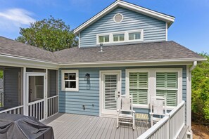 A two-story house with a covered porch, a door leading to a covered entryway, and a small table with chairs.