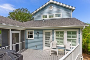 Une maison à deux étages avec un porche couvert, une porte et une fenêtre avec des volets.