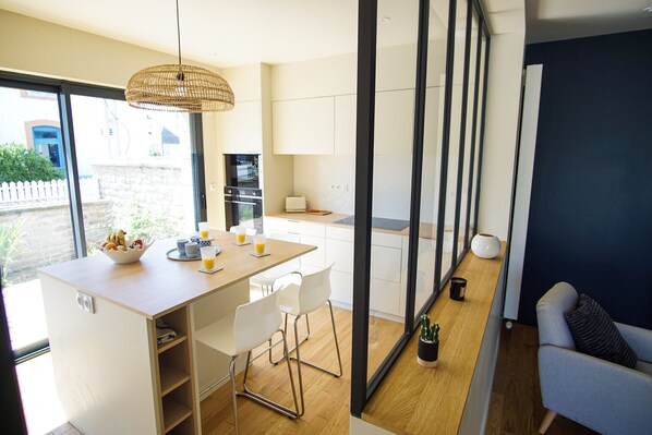 A modern kitchen with a dining area, a large window, and a view of the outside.