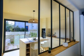 Eine moderne Küche mit Essbereich, großen Fenstern und Blick ins Freie.