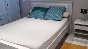 Een netjes opgemaakt bed met twee kussens, een nachtkastje met een lamp en een bruin vloerkleed.