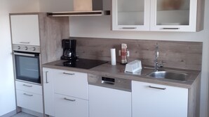 Een moderne keuken met witte kasten, een inbouwoven, een koffiezetapparaat en een gootsteen.
