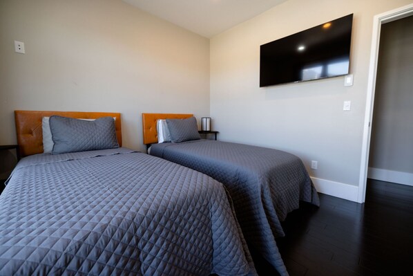 A bedroom with two beds, a TV on the wall, and a door.