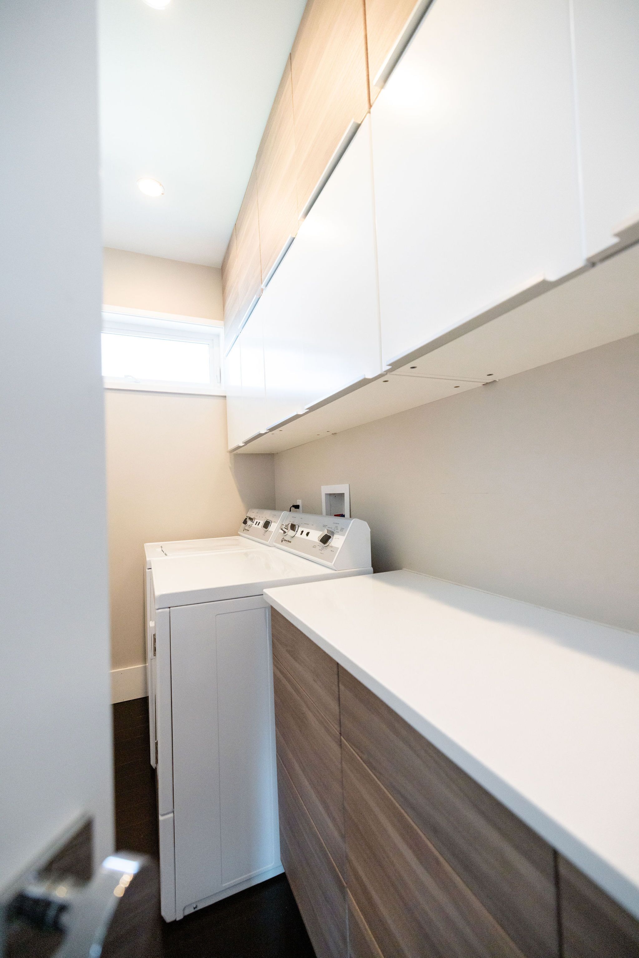 A laundry room with a washing machine and dryer, wooden cabinets, and a countertop.