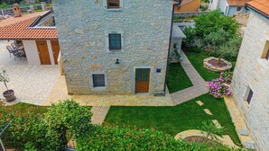 A stone building with a tiled roof, a small garden, and a paved patio area. - Villa Olea in Barat  - Haus für 6-8 Personen (Kanfanar)