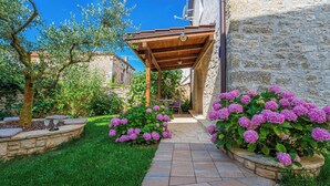 A stone building with a wooden pergola, a stone pathway, and pink hydrangea bushes. - Villa Olea in Barat  - Haus für 6-8 Personen (Kanfanar)