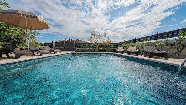 A swimming pool with clear blue water, surrounded by lounge chairs and umbrellas. - Villa Olea in Barat  - Haus für 6-8 Personen (Kanfanar)