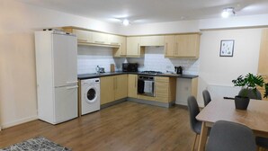 A compact kitchen with a washing machine, a stove, and a dining area with chairs. - Fabulous, 2 bed apt, 10 mins from City Centre (Glasgow)