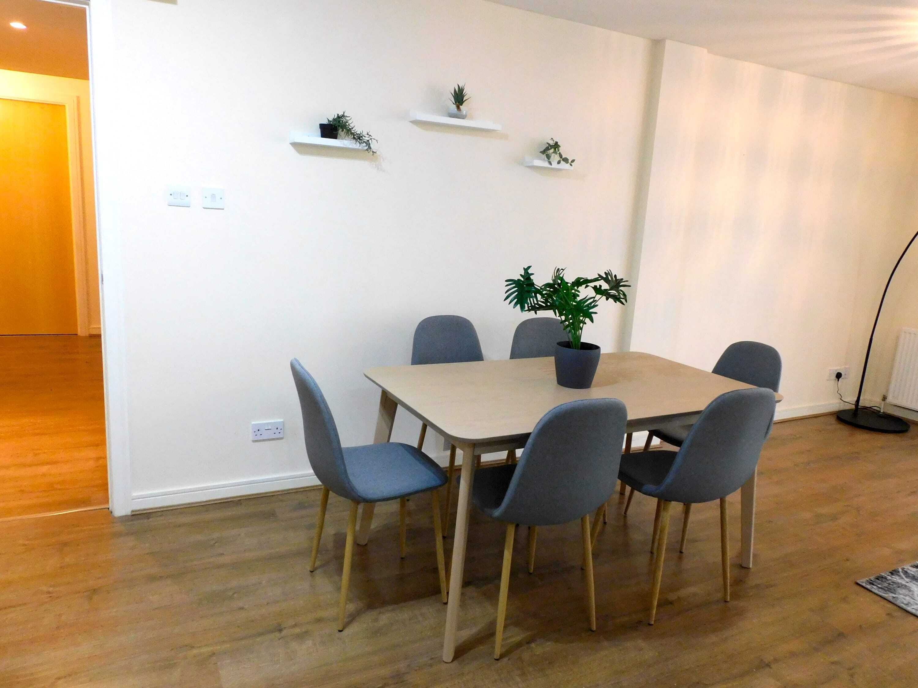 A dining area with a table, chairs, and potted plants.