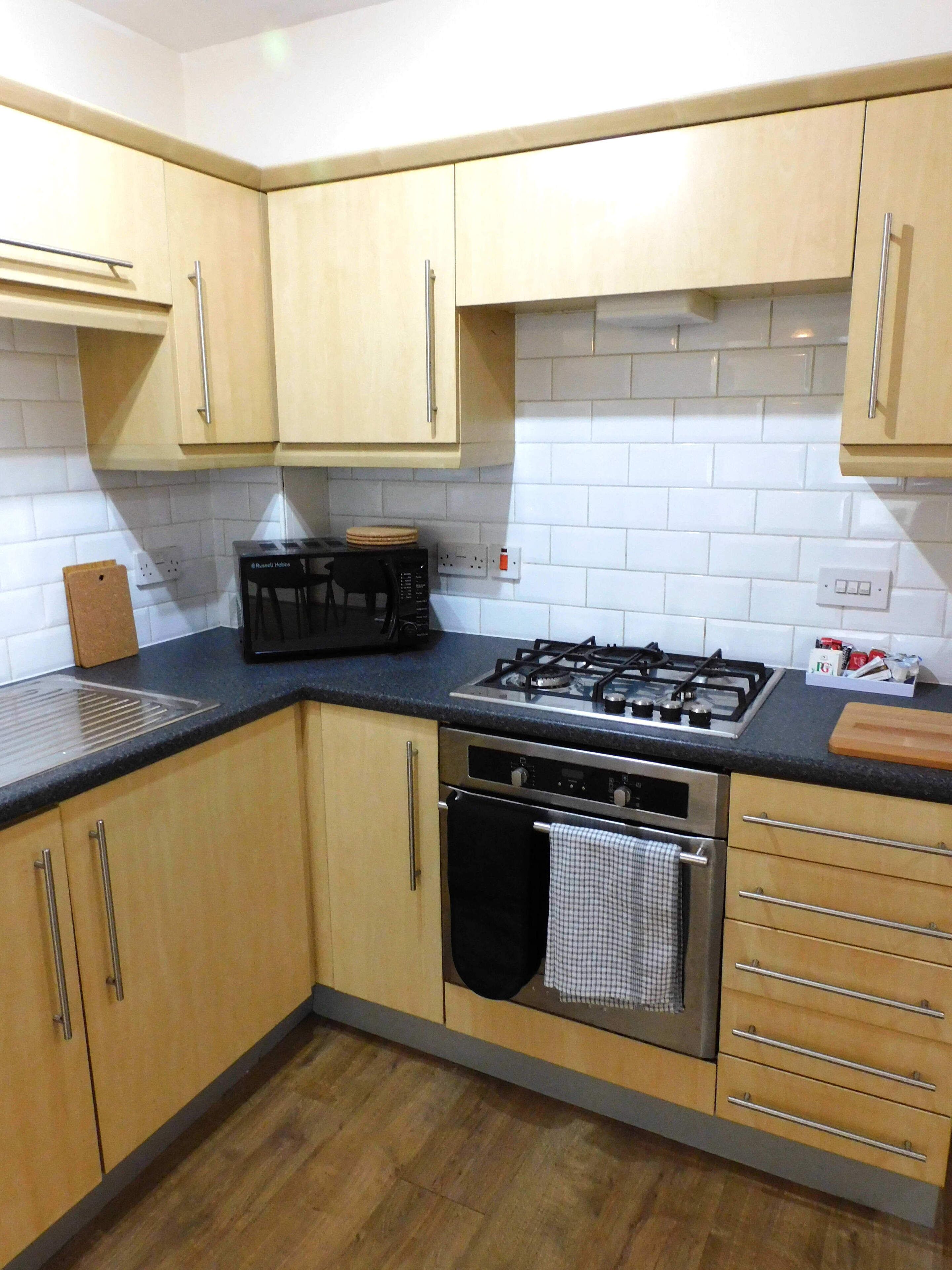 A kitchen with wooden cabinets, a gas stove, an oven, and a black countertop.