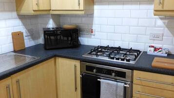 A kitchen with wooden cabinets, a gas stove, an oven, and a black countertop.