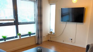 A living room with a sofa, a coffee table, a flat-screen TV, and a window with blinds. - Fabulous, 2 bed apt, 10 mins from City Centre (Glasgow)