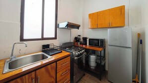 Una cocina pequeña con un fregadero, estufa, microondas y armarios de madera.