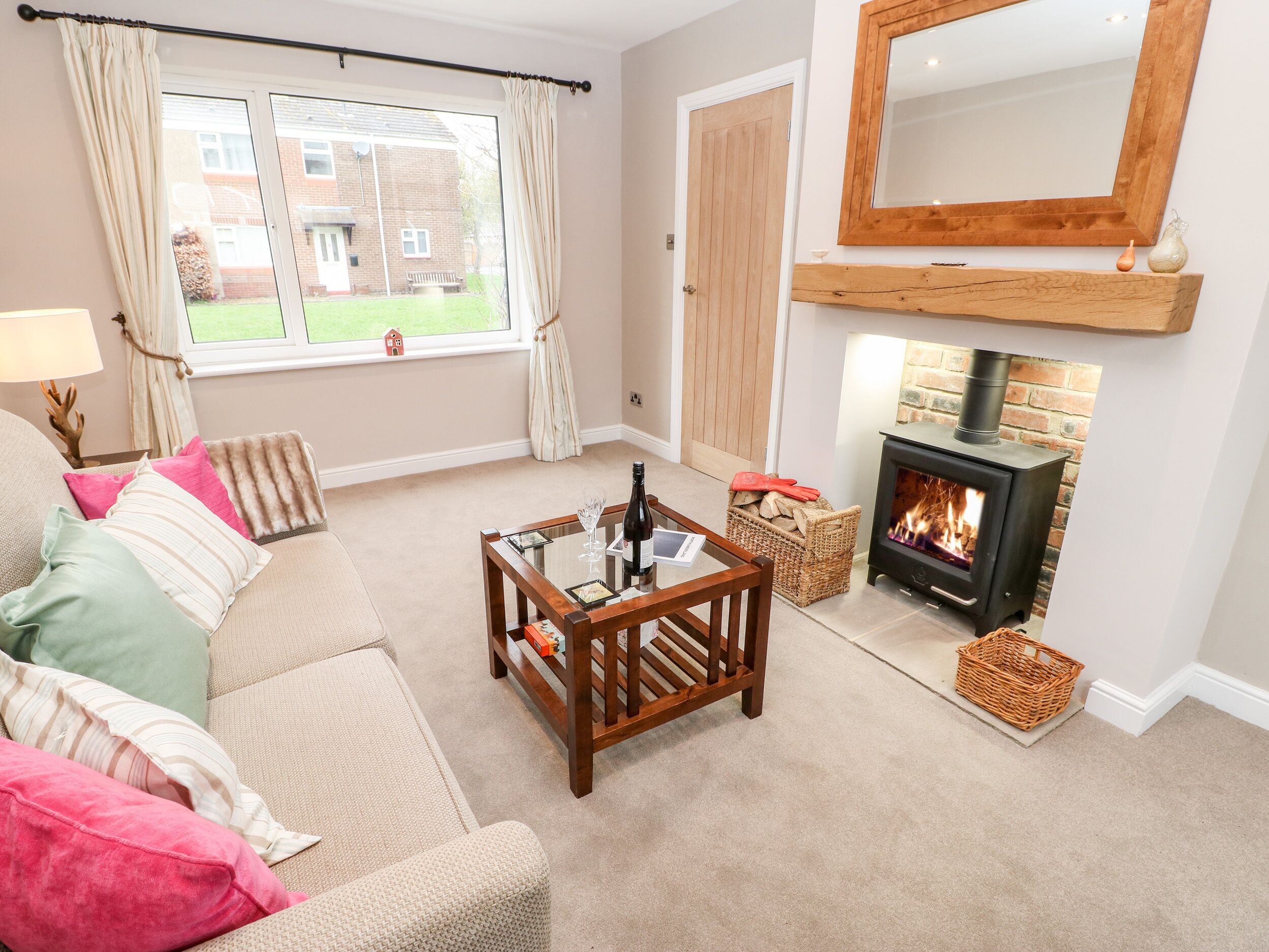 A cozy living room with a sofa, a coffee table, a fireplace, and a view of the outside.