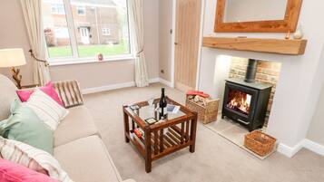 A cozy living room with a sofa, a coffee table, a fireplace, and a view of the outside.