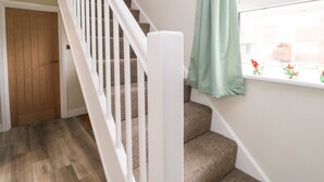 A staircase with white railings, carpeted steps, and a window with a green curtain. - Willows (Corbridge)