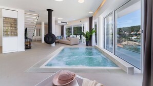 Um interior moderno com uma grande janela, uma banheira de hidromassagem e uma escadaria.