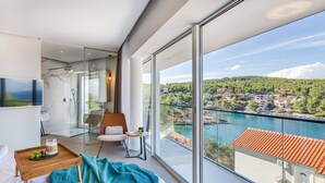 Quarto moderno com uma janela grande, uma cama, mesa de cabeceira com bandeja e uma cadeira.