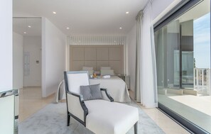 Relax in a spacious room with a large bed, comfortable seating area, and balcony access.