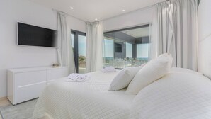 A modern bedroom with a large bed, a flat-screen TV, and a balcony with a glass door. - Luxury Villa Nimai Luce Istria with Heated Pool (Kastelir)