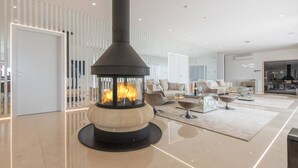A modern living room with a central wood-burning stove, a sofa, a coffee table, and a dining area. - Luxury Villa Nimai Luce Istria with Heated Pool (Kastelir)