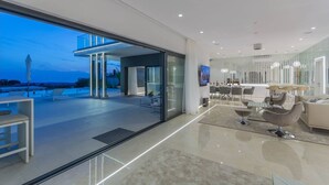 A modern interior with a glass door leading to a balcony, a dining area with a bar, and a seating area with a TV. - Luxury Villa Nimai Luce Istria with Heated Pool (Kastelir)
