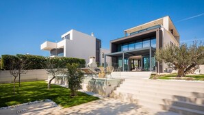 A modern two-story house with a flat roof, large windows, and a well-maintained lawn. - Luxury Villa Idria Zadar with Heated Pool (Petrčane)