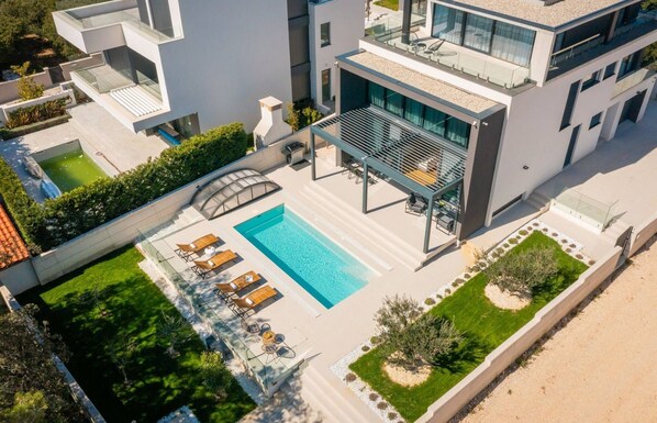 Un immeuble moderne à plusieurs étages, doté d’une piscine sur le toit, d’un espace extérieur aménagé et d’un jardin bien entretenu.