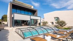 A modern building with a swimming pool, lounge chairs, and a covered patio area. - Luxury Villa Idria Zadar with Heated Pool (Petrčane)