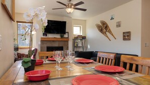 A dining area with a wooden table set for four, red plates, and clear glassware.