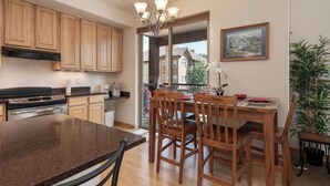 A modern kitchen with wooden cabinets, a granite countertop, and a dining area with wooden chairs and a table.