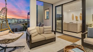 Una sala moderna con un sofá, un sillón colgante y vistas a la ciudad al atardecer.