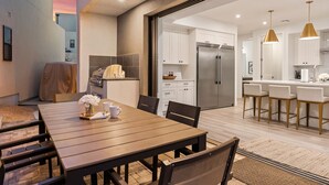 Una cocina moderna con armarios blancos, un refrigerador de acero inoxidable y una barra con taburetes.