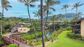 A tropical resort with a pool, palm trees, and a bridge.