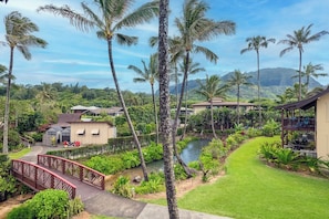 A tropical resort with a water feature, palm trees, and a bridge.