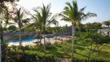 A resort pool area with palm trees, lounge chairs, and a clear view of the water.