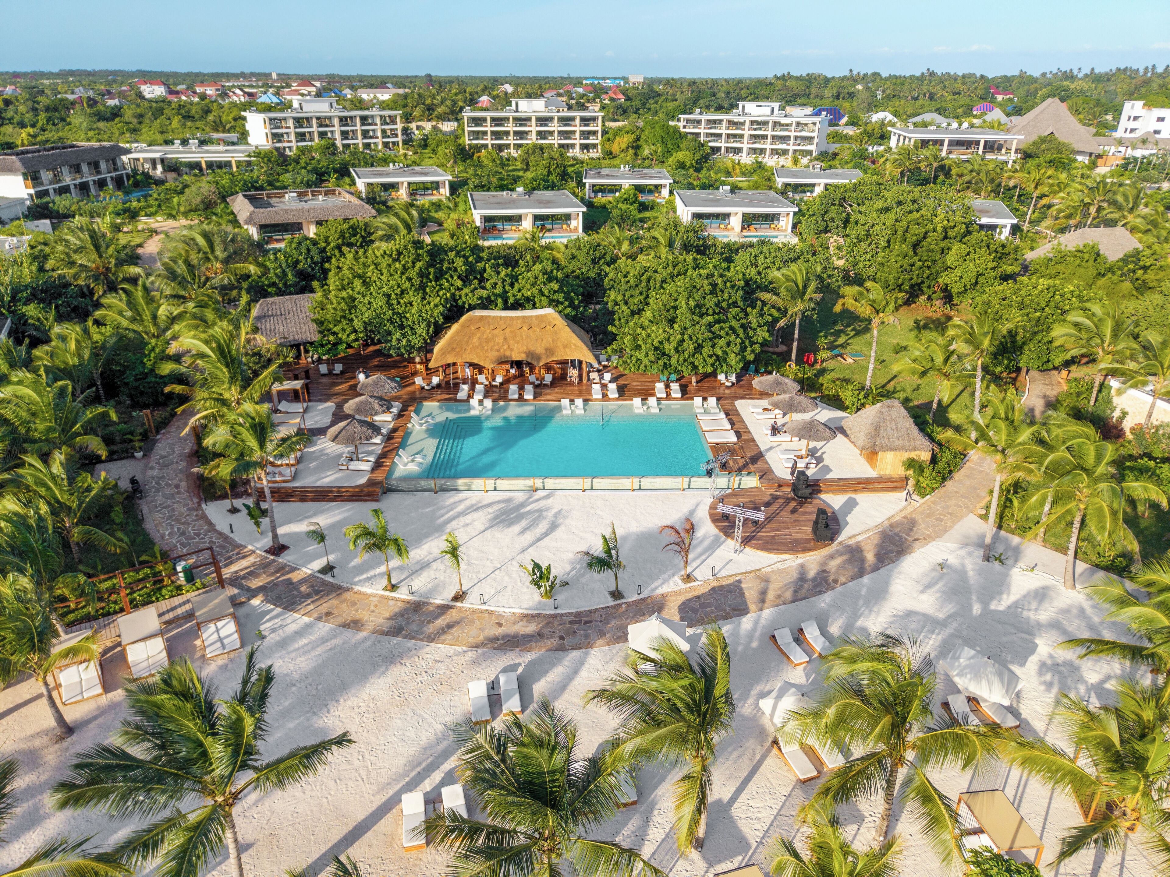 Un resort con piscina central, tumbonas y palmeras.