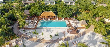 Un resort con piscina central, tumbonas y palmeras.