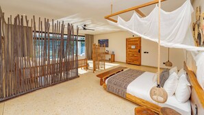 A spacious bedroom with a large bed, a wooden bench, a hanging canopy bed, and a view of the outdoors.