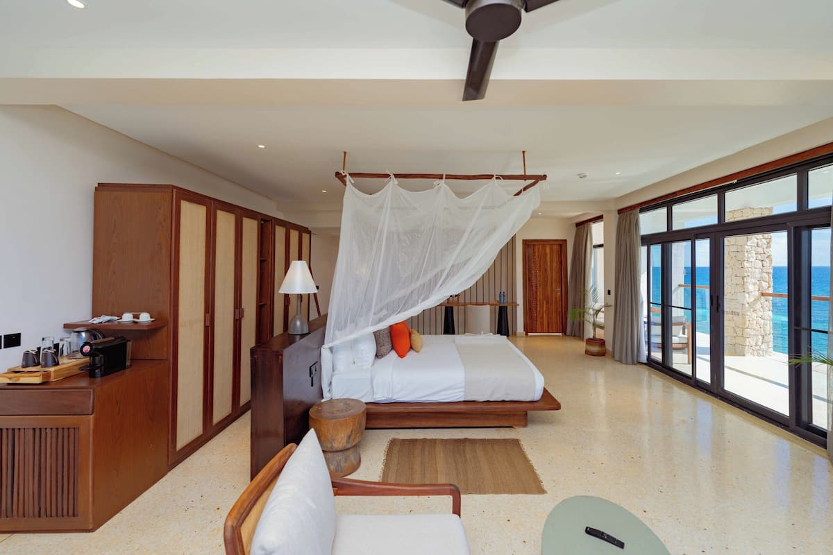 Un dormitorio moderno con una cama grande, un escritorio y vistas al océano.