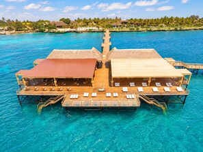A floating hotel with overwater bungalows, each with a thatched roof and a deck with lounge chairs. - Kwanza Resort By SUNRISE (Kizimkazi)