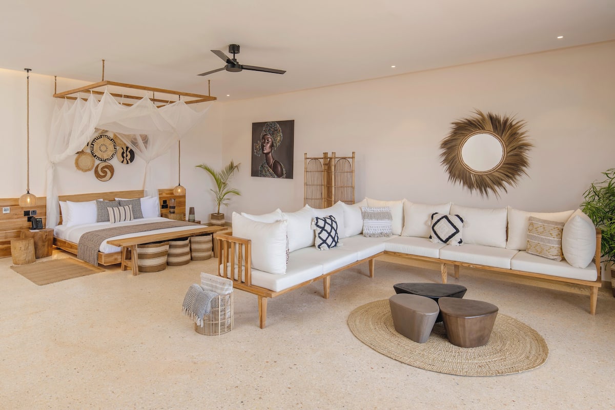 Un dormitorio moderno con cama, sofá, ventilador de techo y un elemento decorativo en la pared.