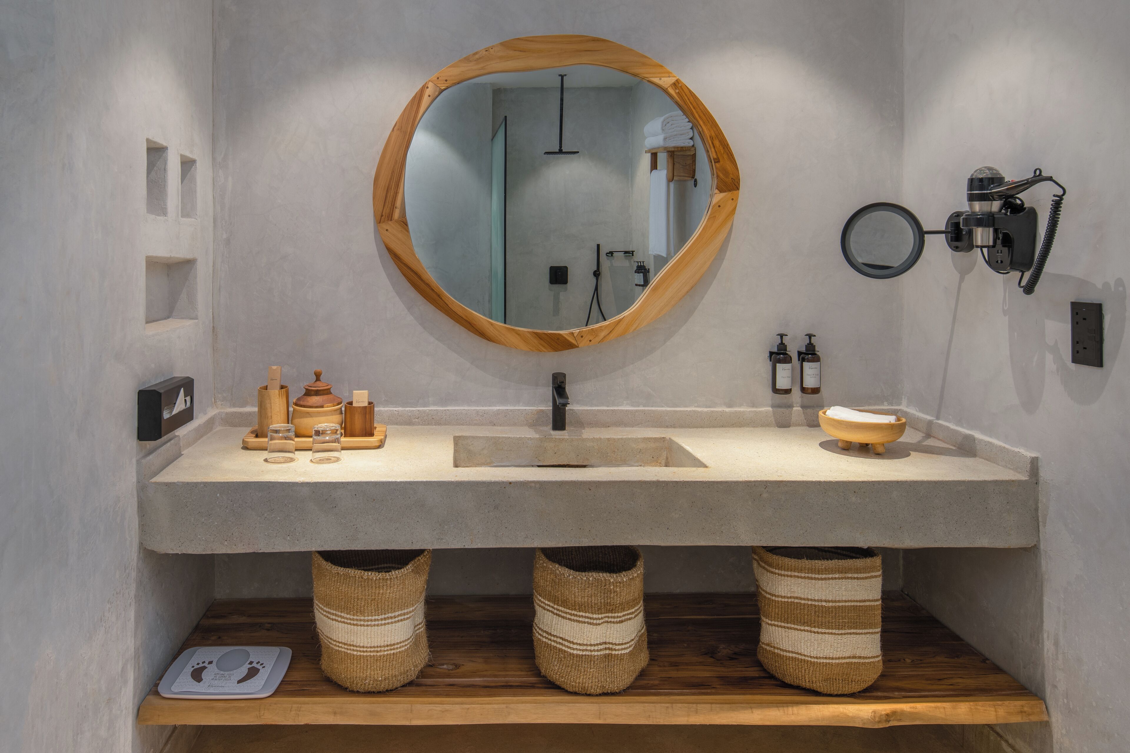 A bathroom with a round mirror, a sink, and wooden baskets.