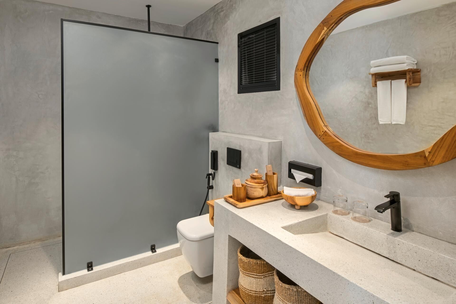 Un baño moderno con cabina de ducha de vidrio, inodoro, lavamanos con bandeja de madera y un espejo grande.
