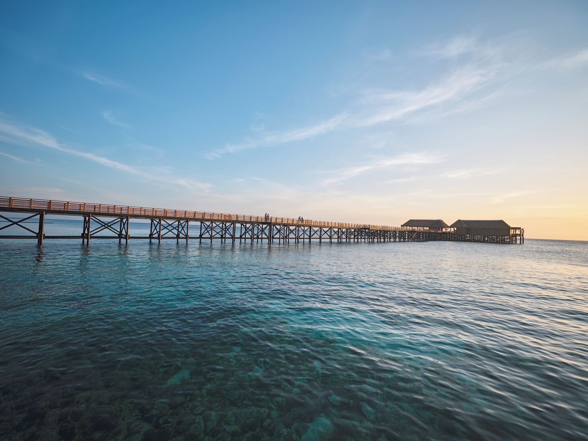 A pier extending into calm waters with clear visibility of the seabed.